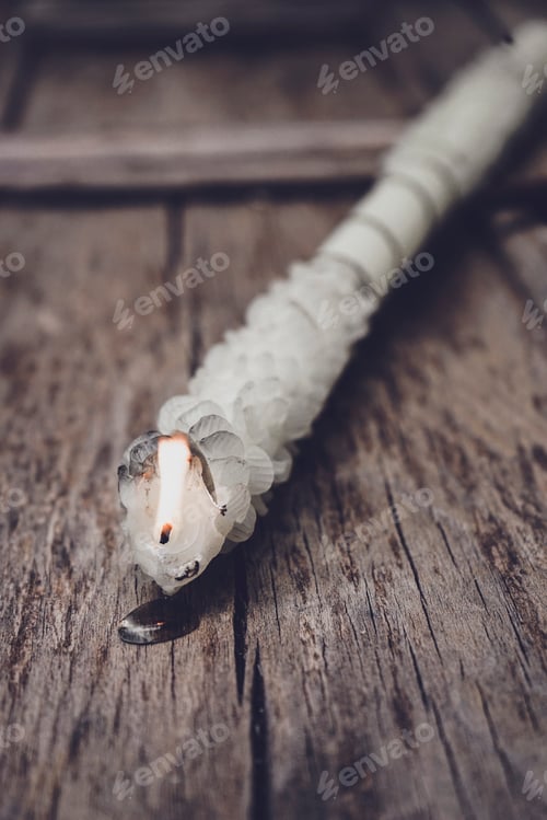 Preview: Hand craft white candle with a flame against old wooden background