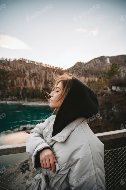Preview: Beautiful blonde young woman traveler enjoys panoramic view on autumn mountains and Katun river