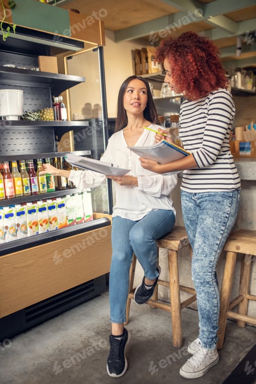 Preview: Young businesswomen discussing drinks in their cafeteria