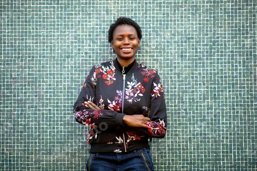 Preview: Happy young african woman smiling by green mosaic wall