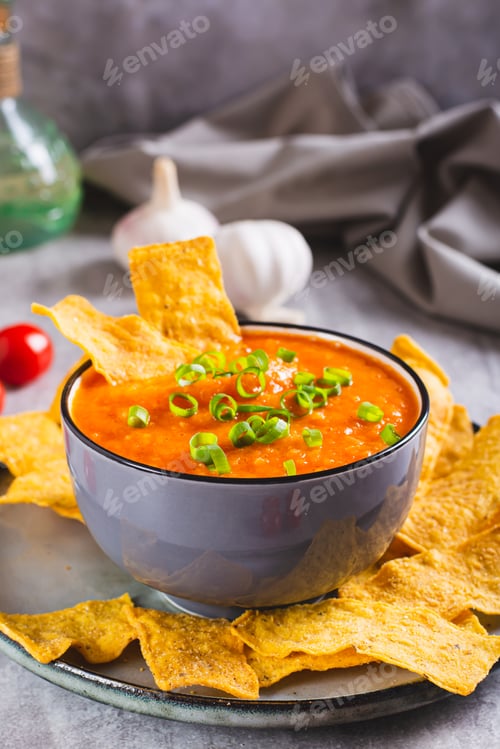 Preview: Traditional mexican salsa sauce in a bowl and corn chips on a plate vertical view