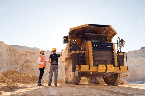 Preview: Standing near haul truck and talking about document. Two men in uniform are working together