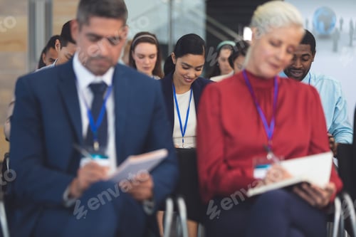 Preview: Businesswoman writing on notepad in business seminar in office building