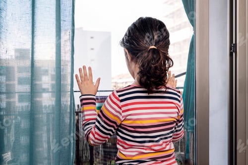 Preview: little girl looking through the window at home