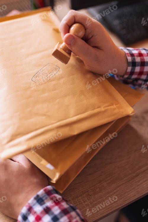 Preview: Man putting stamp on envelope sending mail
