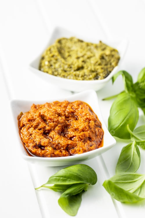 Preview: Green basil and red tomato pesto dip sauce and basil leaves.