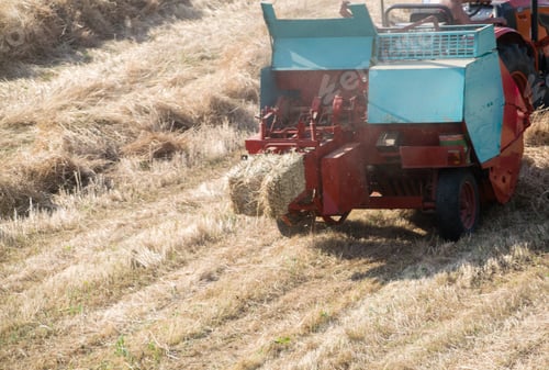 Preview: High angle shot of a tractor collecting haystacks in a hayfield