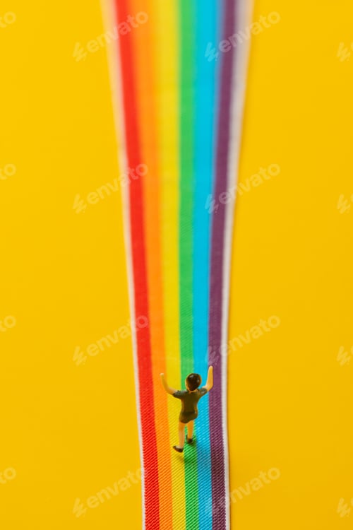 Preview: little boy figure stand on rainbow LGBT strip on yellow background