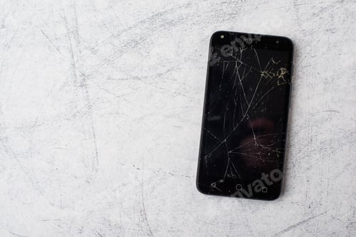 Preview: Closeup shot of a cracked smartphone against a rusty wall background