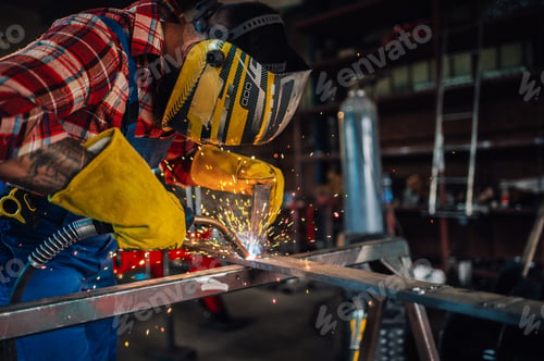 Preview: Skilled worker in a protective gear welding metal with concentration.