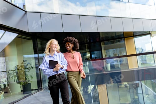 Preview: Two Professional Women Sharing a Joyful Conversation at a Modern Office Building