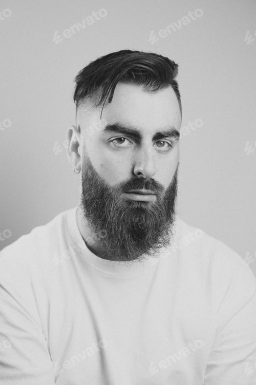 Preview: Portrait of a young bearded man smiling to camera with a white background