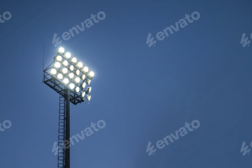 Preview: Low angle closeup shot of stadium lights under a dark blue sky