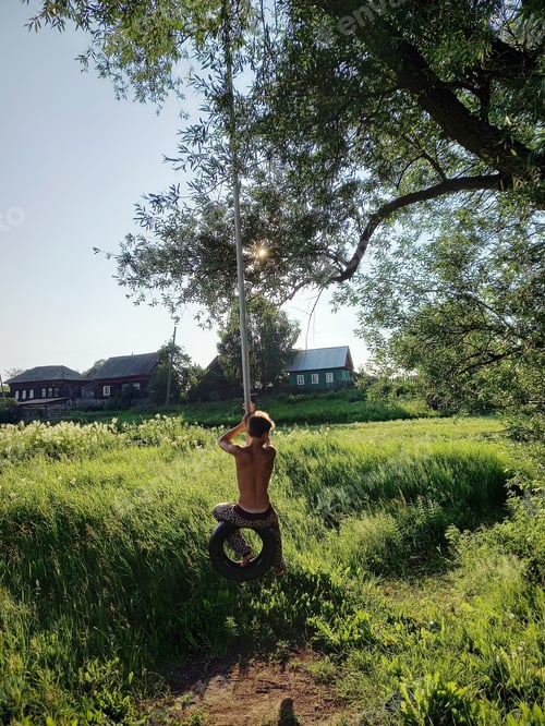 Preview: Boy in countryside swing on whell on tree