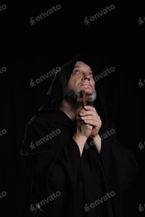 Preview: mysterious medieval priest with wooden cross looking up isolated on black