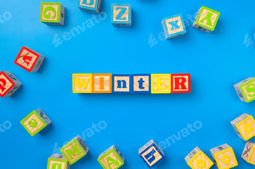 Preview: Winter. Wooden colorful alphabet blocks on blue background, flat lay, top view