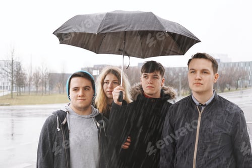 Preview: group of young urban teenage friends under one umbrella