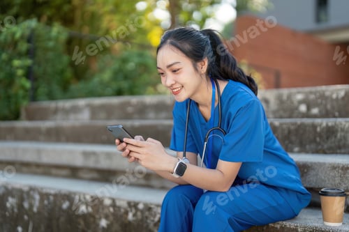 Preview: Asian nurse with coffee, texting on steps outdoors