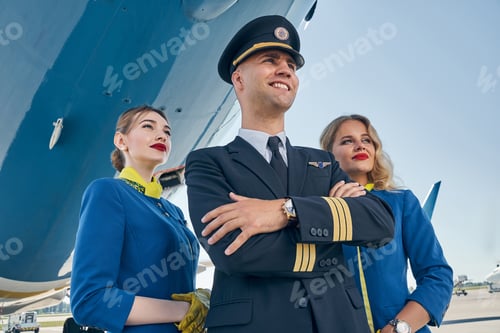 Preview: Dreamy stewardesses standing behind the pilot with folded arms