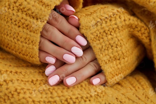 Preview: Female hands with oval nails, matte pink manicure close-up on a knitted sweater background.