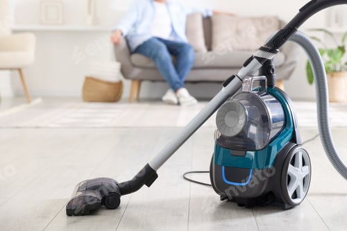Preview: Man resting on sofa at home, focus on vacuum cleaner
