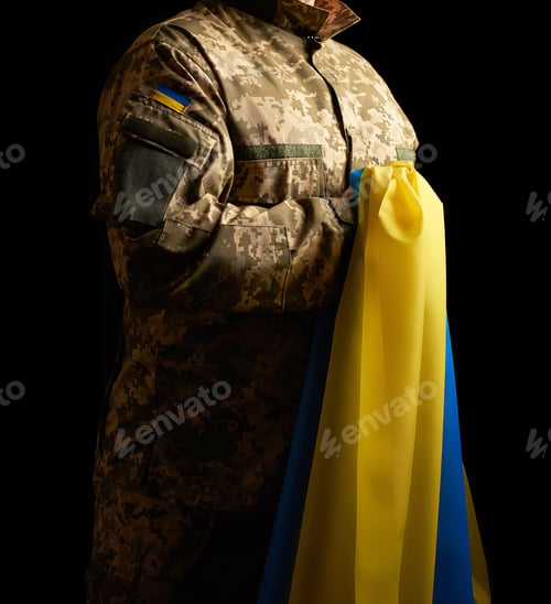 Preview: Ukrainian soldier holds in his hand the yellow-blue flag of the state