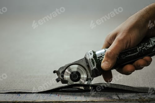 Preview: Closeup shot of male hand using portable cloth cutter