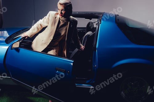 Preview: attractive and stylish woman in suit standing near retro car