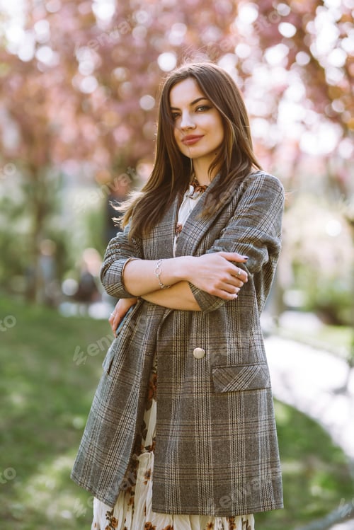Preview: Beautiful young woman near tblooming spring tree. Attractive girl enjoying her time outside in park.