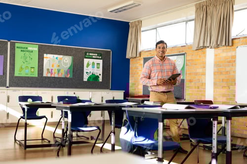 Visualização: Feliz professor birracial masculino com tablet na sala de aula do ensino fundamental, espaço de cópia