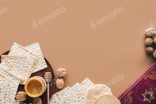 Preview: top view of traditional book with text in hebrew and matza with honey on brown surface