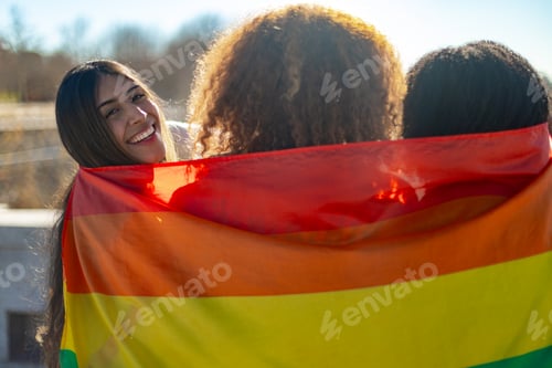 Preview: Three young women holding rainbow flag celebrating gay pride