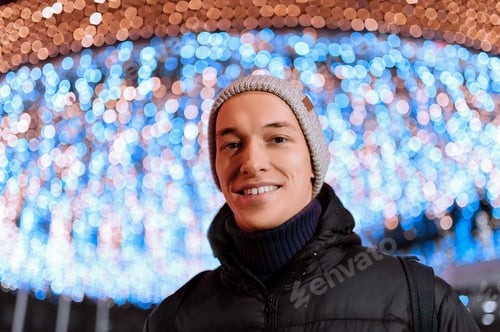 Preview: City Night Portrait Of A Handsome And Young Guy Warmly Dressed Against A Background Of Lights In