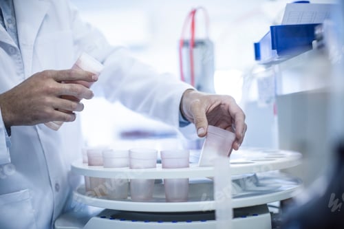 Preview: Mid adult man inserting test cups in laboratory