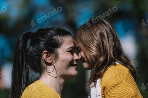 Preview: Little cute child baby girl kiss on cheek and hug, embrace with happy pretty woman in green park.
