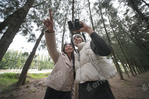 Preview: Friends enjoying nature while birdwatching in a lush forest during daytime