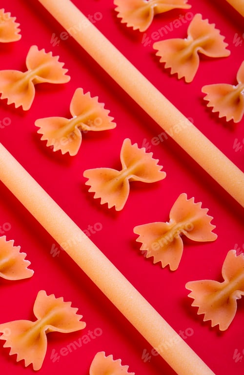 Preview: side view of pattern of macaronis as farfalle and bucatini on red background