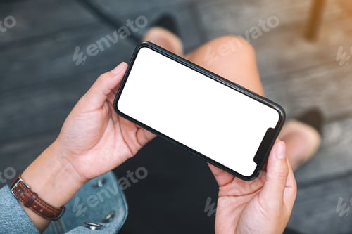 Preview: Top view mockup image of a woman holding a black mobile phone with blank white desktop screen