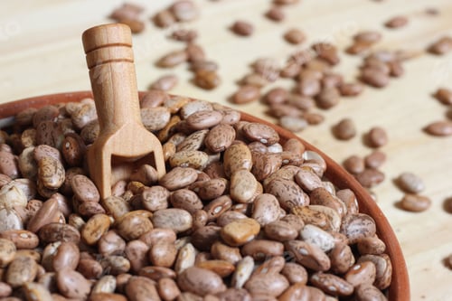 Preview: Dry Pinto Beans in Clay Bowl With Wooden Spoon in Rustic Kitchen