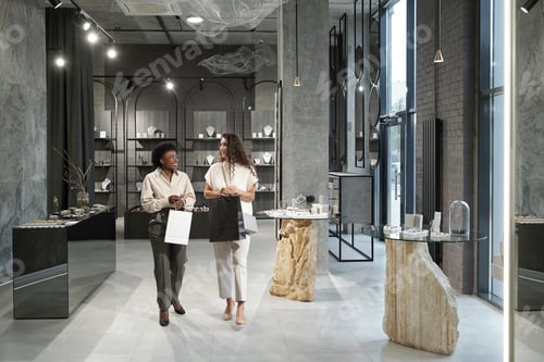 Preview: Two young intercultural females having discussion while moving along jewelry boutique
