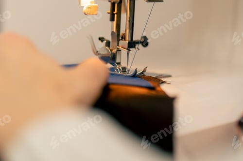 Preview: close-up in a sewing workshop on a machine the seamstress master makes cut on a blue fabric