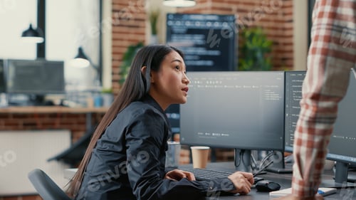 Preview: Database developer pointing pencil at computer screen with software compiling code