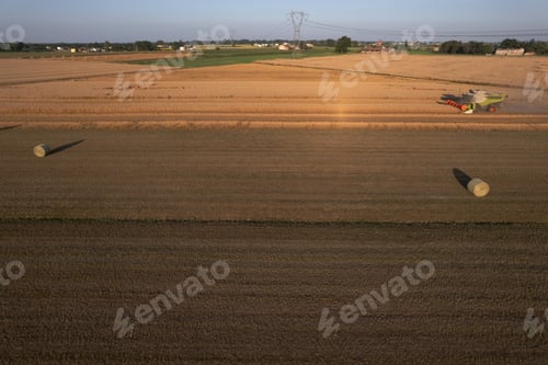 Preview: aerial view of hay ball of wheat straw in large field at early sunset in summer time
