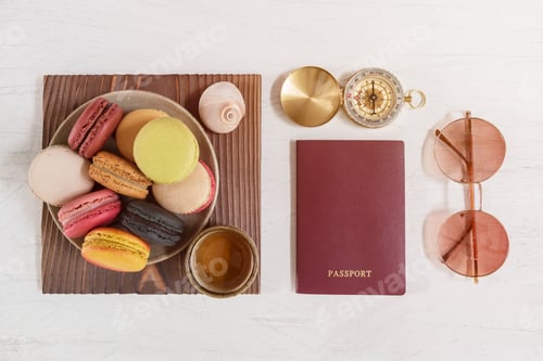 Preview: Travel concept, red passport on white table with compass, sunglasses and macaroons with tea cup.