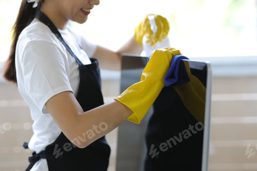Preview: Young Asian cleaning woman uses a towel to clean a computer.