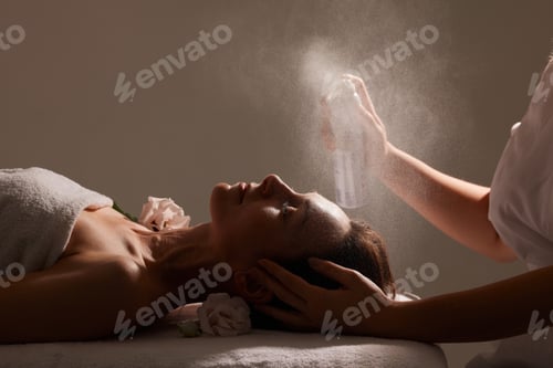 Preview: cosmetologist sprays a refreshing spray on a girl’s face on a white background