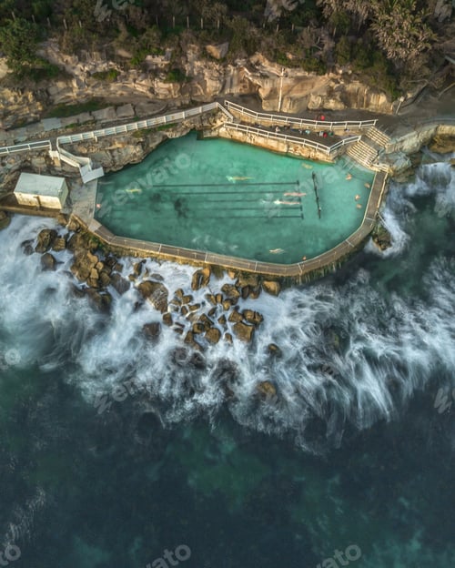 Preview: Aerial shot of people swimming in a large pool built on the rocky coast in Thailand