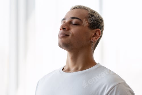 Preview: Young man standing with eyes closed, finding relaxation and balance through meditation