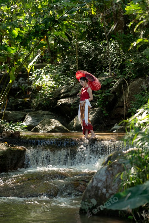 Preview: Young Asian woman in traditional Thai clothing holding a red paper umbrella