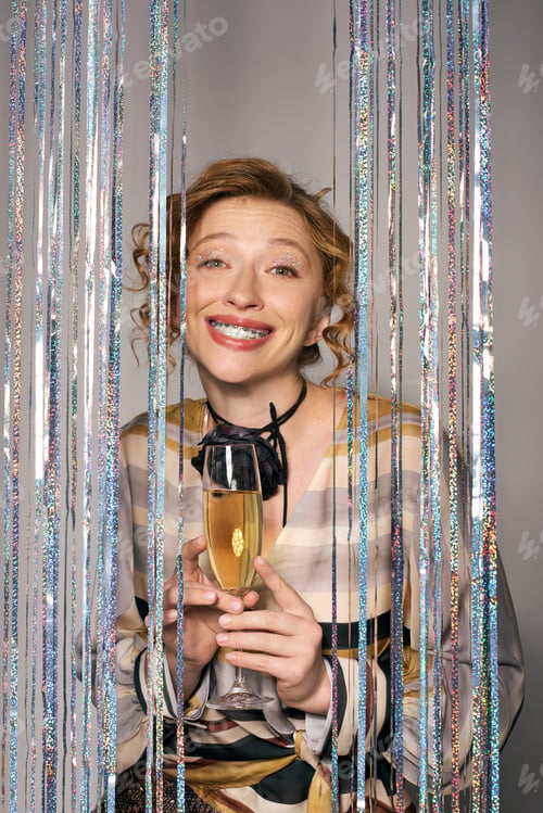 Preview: A young woman joyfully holding a drink while surrounded by festive decorations during a celebration